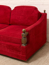 Load image into Gallery viewer, A close-up of a red upholstered loveseat or sofa section with carved wooden armrest posts, shown against a white brick wall and light rug.
