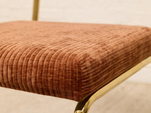 Load image into Gallery viewer, Close-up of a cushioned upholstered stool or chair seat in a ribbed brown corduroy fabric, with a polished gold metal frame visible against a light neutral background.