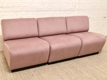 Load image into Gallery viewer, A three-seat modular sofa upholstered in dusty pink velvet, positioned on a textured beige rug against a white brick wall.