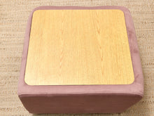Load image into Gallery viewer, A square ottoman with a dusty mauve-purple velvet fabric frame and a light natural wood grain top, shown on a textured beige woven rug.