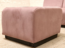 Load image into Gallery viewer, A dusty pink velvet ottoman with a dark wood base, shown in a close-up shot on a textured beige rug.