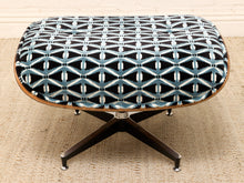 Load image into Gallery viewer, A mid-century modern lounge chair or ottoman with a black and light blue geometric patterned fabric cushion, supported by a dark wood star base with silver metal feet, set on a beige woven rug.
