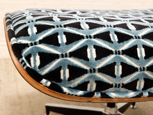 Load image into Gallery viewer, Close-up of a curved upholstered chair or stool with a black, light blue, and white geometric patterned fabric and a light wood rim.