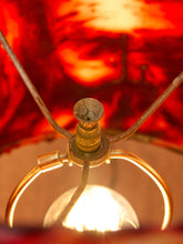 Load image into Gallery viewer, Close-up of a vintage-style lamp with a glowing warm bulb, brass-toned metal frame, and a red fabric shade in the background.
