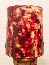 Load image into Gallery viewer, A cylindrical lampshade with a glossy, marbled pattern of deep red, dark burgundy, and cream, displayed against a white brick wall background.