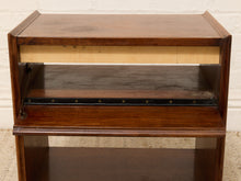 Load image into Gallery viewer, A mid-century modern wooden nightstand or end table with a dark brown wood finish, featuring a pull-out shelf with brass hardware and a light wood accent strip.