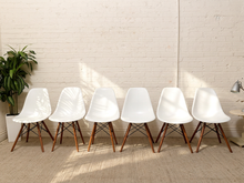 Load image into Gallery viewer, Set of six white molded shell dining chairs with tapered wood legs and black metal cross-braced bases