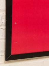 Load image into Gallery viewer, A close-up of a framed wall art piece with a bright red center and a thick black frame, mounted against a white painted brick wall.