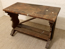 Load image into Gallery viewer, An antique dark brown wooden writing desk with a distressed finish, featuring a top surface, a lower shelf, and carved legs, set against a white brick wall and beige carpet.