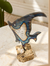 Load image into Gallery viewer, A decorative stained glass fish sculpture mounted on a natural stone base with a small white shell, displayed on a light marble surface with soft shadows.