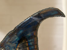 Load image into Gallery viewer, A close-up of a curved, iridescent shell or horn-like object with deep blue, teal, and brown tones against a soft beige background.