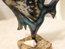 Load image into Gallery viewer, A close-up of a decorative sculpture featuring a translucent, iridescent wing-like form with blue, purple, and gold tones, mounted on a stone base with a small seashell placed in front.