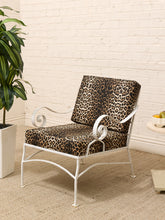 Load image into Gallery viewer, A white metal outdoor armchair with leopard-print cushions, set against a white brick wall with a potted plant on the left.