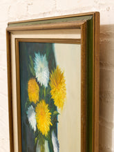 Load image into Gallery viewer, A framed floral painting featuring yellow, white, and blue flowers, shown at an angle against a white brick wall.