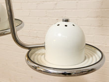 Load image into Gallery viewer, A close-up of a vintage-style white ceramic or enamel wall sconce with a rounded dome shade, small ventilation holes, and a polished chrome metal arm and circular base against a light brick wall.