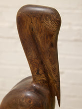 Load image into Gallery viewer, Close-up of a carved wooden sculpture depicting a bird's head and neck, showcasing rich dark brown wood grain against a light off-white background.
