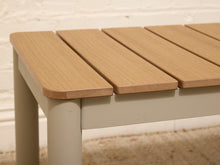 Load image into Gallery viewer, Close-up of a slatted wooden bench or table top with a light natural wood finish and a white frame, set against a white brick wall and beige rug.