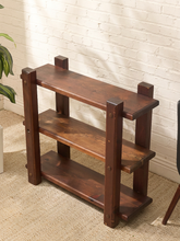 Load image into Gallery viewer, A three-tier wooden shoe rack with a dark brown finish, shown in a home setting against a white brick wall and beige carpet.