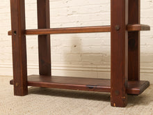 Load image into Gallery viewer, A close-up of a dark brown wooden shelf or stand with two horizontal slats, shown against a white painted brick wall and beige carpet.