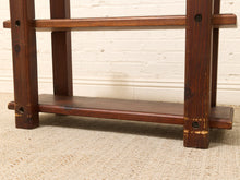 Load image into Gallery viewer, Close-up of a dark brown wooden shelf or stand with visible grain and distressed wear, set against a white brick wall and beige rug.