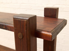 Load image into Gallery viewer, Close-up of a dark brown wooden table corner showing the joinery, a round metal knob, and a small square block support against a white brick wall background.