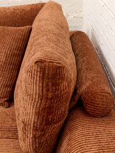 Load image into Gallery viewer, Close-up of a brown corduroy sofa with matching cushions, showing the ribbed fabric texture against a white brick wall background.