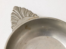 Load image into Gallery viewer, Close-up of a silver metal bowl with a decorative shell-shaped handle, resting on a textured white fabric background.
