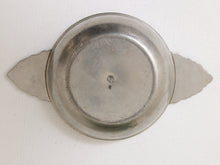 Load image into Gallery viewer, A vintage silver-toned metal plate with decorative leaf-like extensions on either side, photographed from directly above on a white textured fabric background.