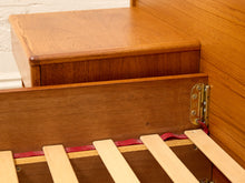 Load image into Gallery viewer, Close-up of a wooden bed frame or nightstand with a slatted wooden base, showing the wood grain, metal hinge, and red fabric lining.