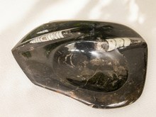 Load image into Gallery viewer, A polished black stone dish with natural white and gray inclusions, photographed on a textured off-white fabric background.