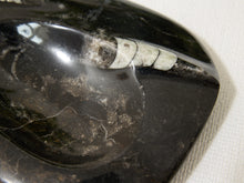 Load image into Gallery viewer, A close-up of a polished black stone or obsidian dish with a white inlay, resting on a textured off-white fabric background.