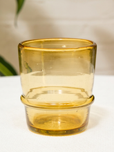 Load image into Gallery viewer, A translucent amber yellow glass tumbler with a thick base, shown stacked with a smaller matching glass on top, set against a soft off-white background.