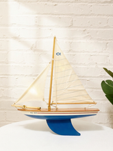 Load image into Gallery viewer, Vintage wooden model sailboat with cream fabric sails, blue and white painted hull, red stripe, and sculptural blue keel