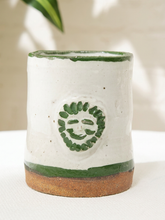 Load image into Gallery viewer, Handmade white glazed ceramic mug with green rim, green base, and raised face motif