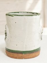 Load image into Gallery viewer, A handmade ceramic cup with a speckled off-white glaze, a dark green rim and base band, and a rustic brown clay foot, shown against a soft neutral background.