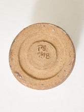 Load image into Gallery viewer, The underside of a round ceramic plate or bowl, showing a textured tan-brown glaze with concentric ring details and a stamped maker's mark reading 'PS 718'.
