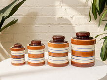 Load image into Gallery viewer, Set of four vintage striped stoneware canisters with brown lids and cream blue and brown bands
