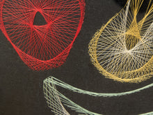 Load image into Gallery viewer, Close-up of a black fabric surface with geometric string art patterns in red, yellow, and pale mint green.