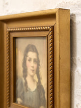 Load image into Gallery viewer, A close-up of an ornate gold picture frame holding a vintage portrait of a young woman, shown against a textured white wall.