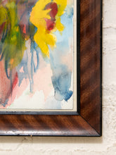 Load image into Gallery viewer, Close-up of a framed abstract watercolor painting showing yellow, blue, green, pink, and red brushstrokes within a dark brown wooden frame against a white textured wall.