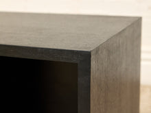 Load image into Gallery viewer, Close-up of a dark wood furniture corner, showing the textured grain of a dark brown or black wood surface against a light beige background.