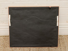Load image into Gallery viewer, The back of a square framed art print or canvas, featuring a black textured surface, a thin copper-toned metal frame, and white hanging clips on the sides, set against a white brick wall and woven rug.