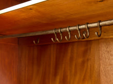 Load image into Gallery viewer, A close-up view of a wooden closet rod with six metal hanging hooks attached inside a wooden cabinet.