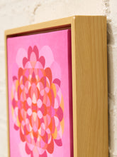 Load image into Gallery viewer, A framed canvas art print featuring a retro-style pink and orange geometric flower design, set in a light natural wood frame against a white brick wall.