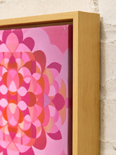 Load image into Gallery viewer, A close-up of a framed canvas print featuring a retro-style pink and magenta geometric floral pattern, set in a light natural wood frame against a white brick wall.