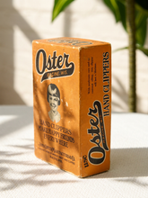 Load image into Gallery viewer, Vintage orange Oster hand clippers advertising box with illustrated portrait and John Oster Manufacturing Co. Racine Wisconsin branding