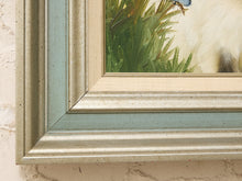 Load image into Gallery viewer, Close-up of a framed artwork corner showing a distressed light blue and beige frame with a painted scene of green reeds and a small blue bird.