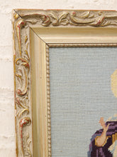 Load image into Gallery viewer, Close-up of an ornate vintage-style frame with carved details and distressed gold, silver, and red paint, showing a light blue needlepoint canvas with part of a colorful embroidered figure.