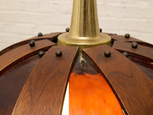 Load image into Gallery viewer, Close-up of a hanging pendant light with a dark brown wood slat canopy, brass metal finial, and a glowing orange glass shade.