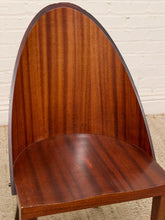 Load image into Gallery viewer, A close-up of a mid-century modern wooden chair with a curved, high backrest and a rich reddish-brown wood grain finish, set against a white brick wall and light beige carpet.
